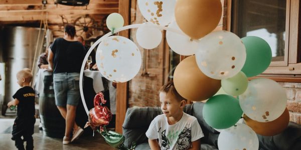 A young boy with balloons at an indoor birthday party gathering.