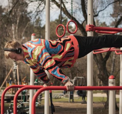 Young adult man exercises on outdoor gym bars in a colorful outfit in Vilnius, Lithuania.